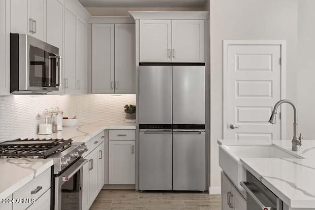 kitchen featuring light stone counters, stainless steel appliances, light hardwood / wood-style floors, and white cabinets