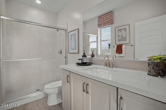 bathroom featuring vanity, toilet, wood finished floors, and a shower stall