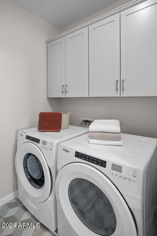 clothes washing area featuring cabinet space, independent washer and dryer, light floors, and baseboards