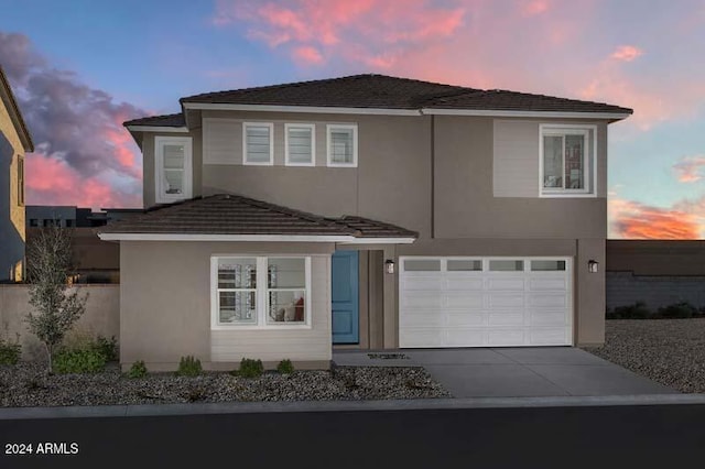 traditional-style house with a garage, stucco siding, and driveway