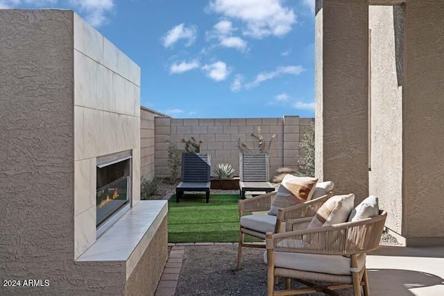 view of patio with fence and a glass covered fireplace