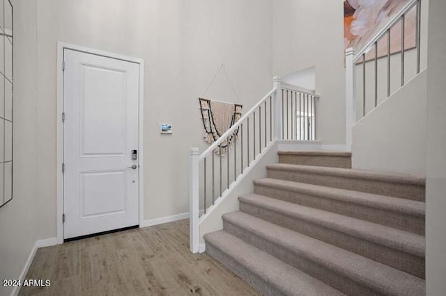 foyer with baseboards, stairway, a high ceiling, and wood finished floors