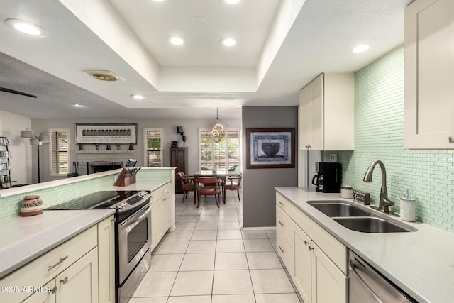 kitchen with appliances with stainless steel finishes, tasteful backsplash, a sink, light countertops, and light tile patterned flooring