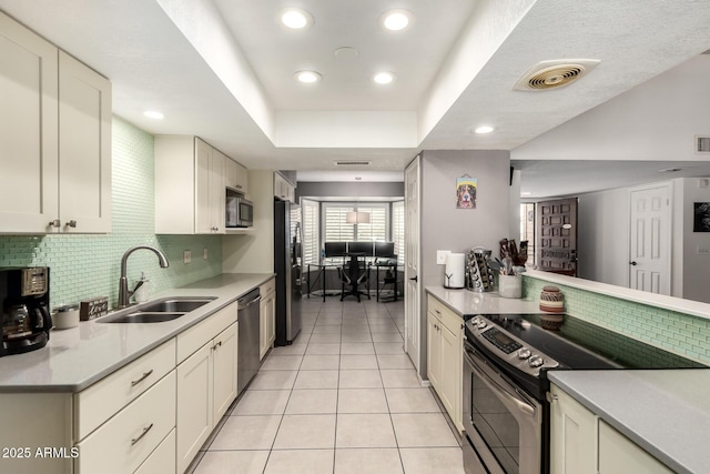 kitchen featuring light countertops, tasteful backsplash, a sink, appliances with stainless steel finishes, and light tile patterned floors