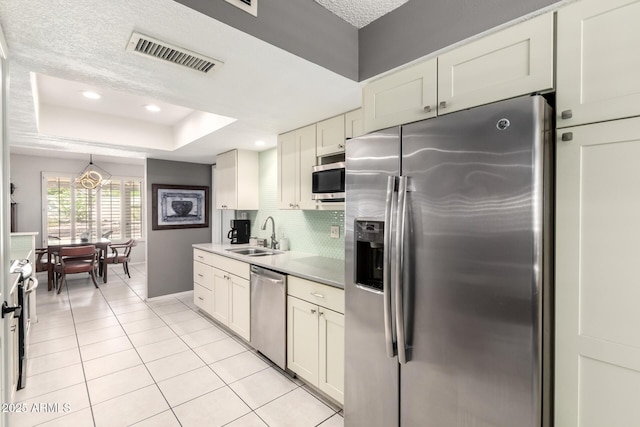 kitchen featuring appliances with stainless steel finishes, a sink, light tile patterned floors, tasteful backsplash, and visible vents