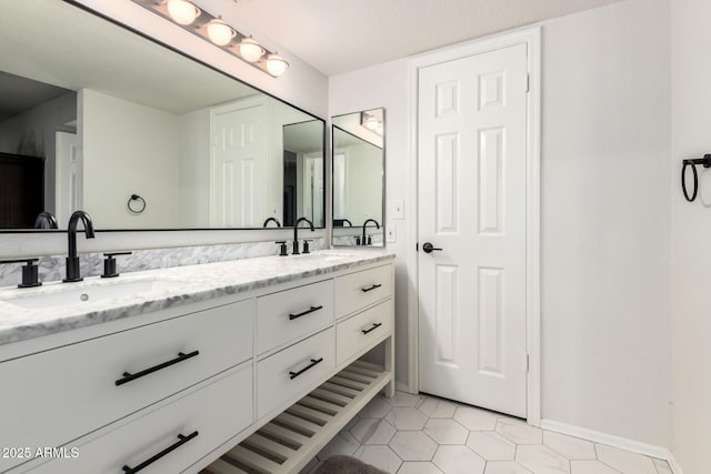 full bath with double vanity, a sink, baseboards, and tile patterned floors