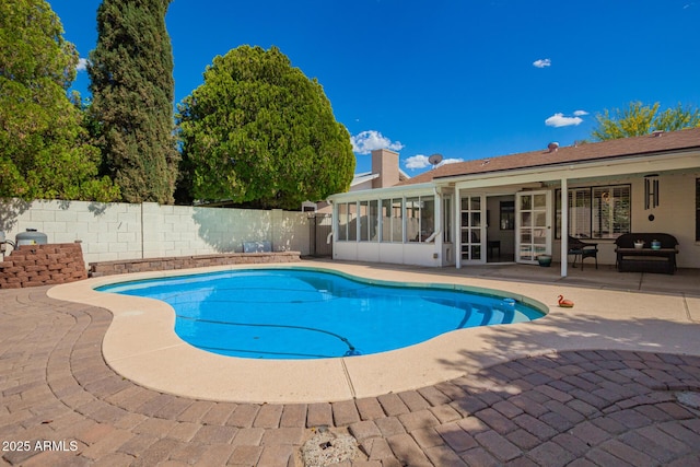 view of swimming pool with a fenced backyard, a fenced in pool, a sunroom, and a patio area