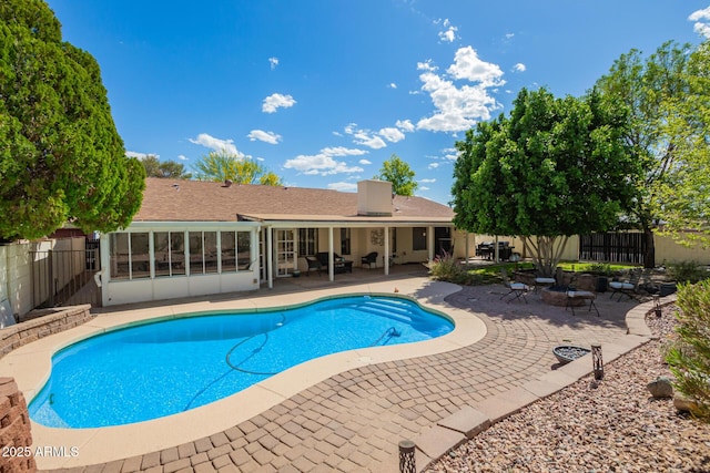 view of swimming pool with a patio, a sunroom, fence, and a fenced in pool
