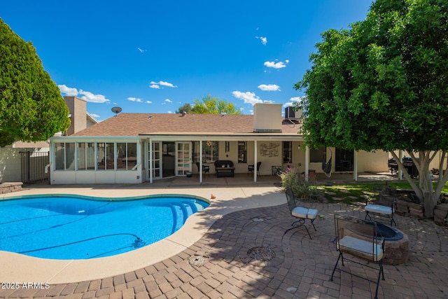 view of swimming pool featuring a fenced in pool, a sunroom, a fire pit, and a patio area