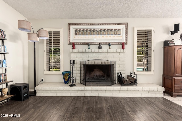 living area featuring baseboards, a textured ceiling, wood finished floors, and a fireplace