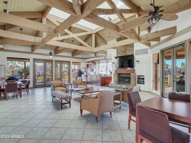 interior space featuring light tile patterned floors, a stone fireplace, french doors, and beamed ceiling