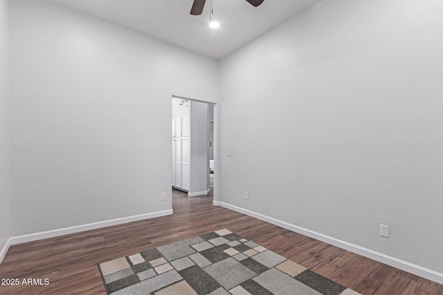 unfurnished room with a ceiling fan, baseboards, and dark wood-style flooring