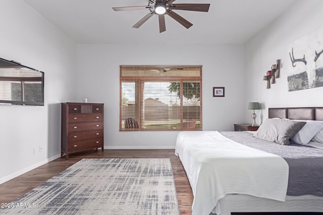 bedroom featuring baseboards, wood finished floors, and a ceiling fan