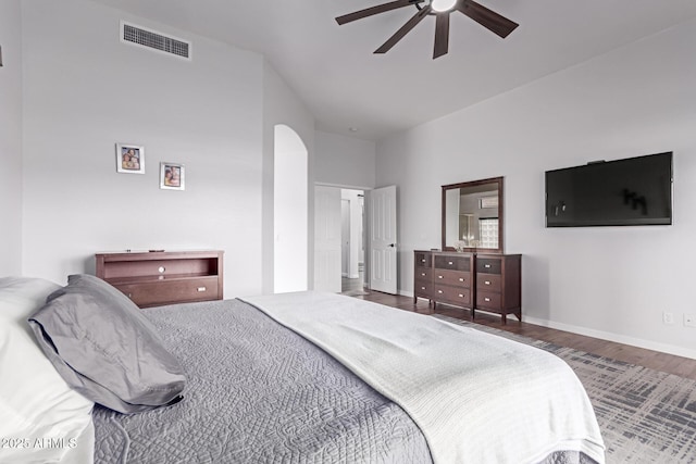 bedroom with visible vents, a ceiling fan, wood finished floors, arched walkways, and baseboards