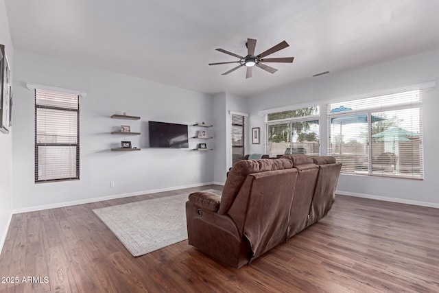 living room featuring visible vents, baseboards, wood finished floors, and a ceiling fan