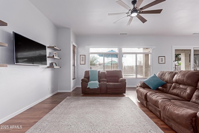 living room featuring a ceiling fan, wood finished floors, visible vents, and baseboards