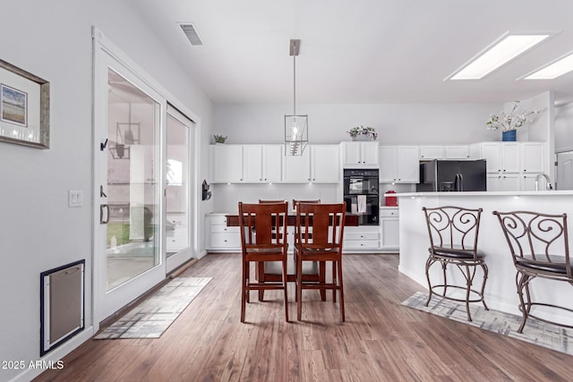 dining room with a skylight, wood finished floors, and visible vents