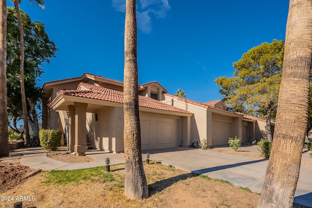 mediterranean / spanish-style house with stucco siding, concrete driveway, an attached garage, and a tile roof