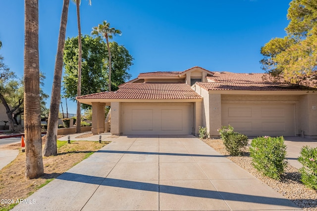 mediterranean / spanish-style home featuring a tile roof, an attached garage, driveway, and stucco siding