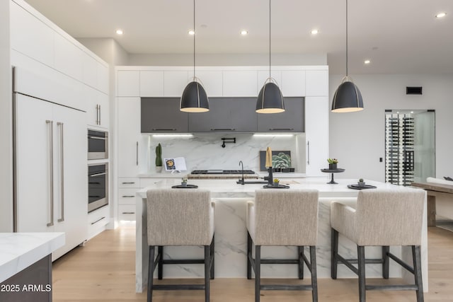 kitchen with stainless steel gas cooktop, paneled built in fridge, light wood finished floors, and modern cabinets