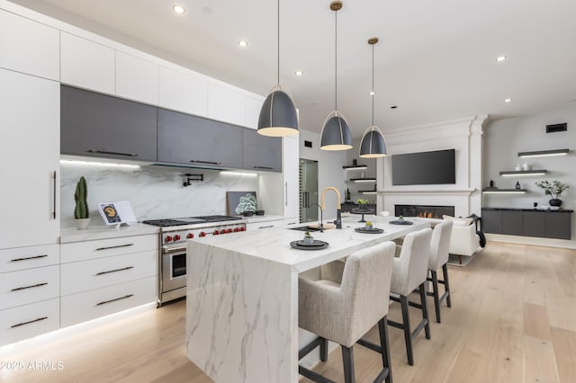 kitchen featuring high end stainless steel range oven, tasteful backsplash, modern cabinets, and a sink