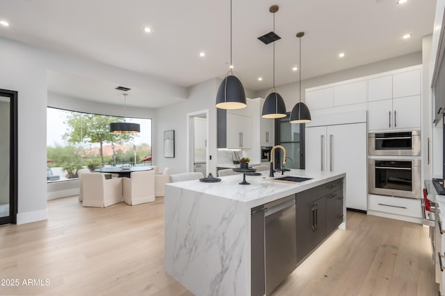 kitchen with a center island with sink, stainless steel dishwasher, paneled fridge, white cabinetry, and a sink