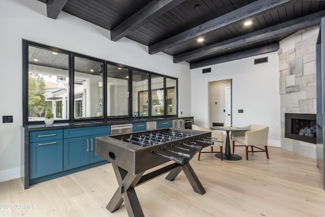 rec room with beam ceiling, light wood finished floors, visible vents, wood ceiling, and a large fireplace