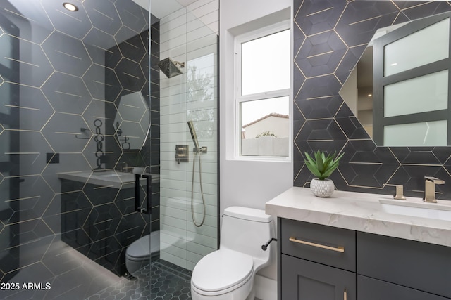 full bath with decorative backsplash, a tile shower, vanity, and toilet