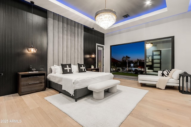 bedroom with a chandelier, wood finished floors, a raised ceiling, and visible vents