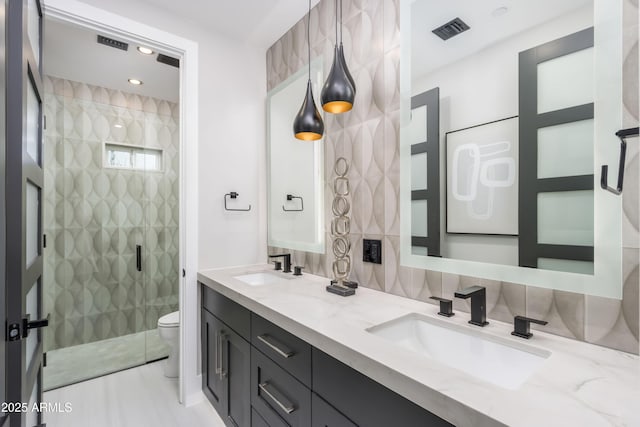 bathroom with a stall shower, visible vents, a sink, and toilet