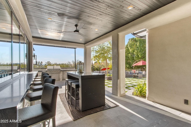 view of patio featuring ceiling fan, exterior kitchen, grilling area, and an outdoor living space