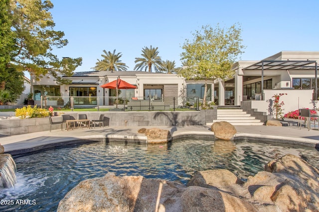 back of property with a patio area and an outdoor pool