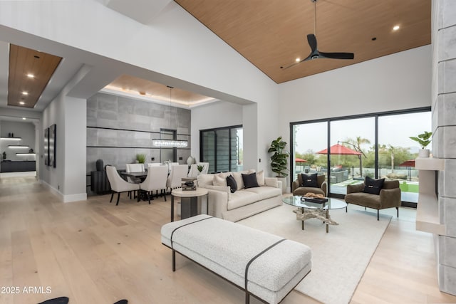 living area with wood ceiling, light wood-style flooring, a high ceiling, and baseboards