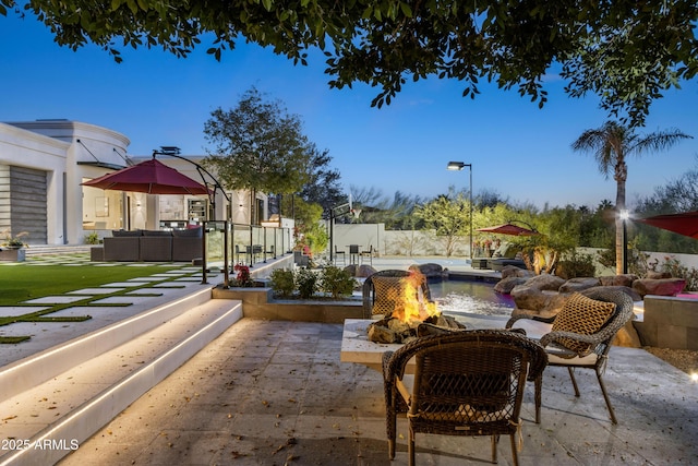 view of patio / terrace featuring fence and an outdoor living space with a fire pit