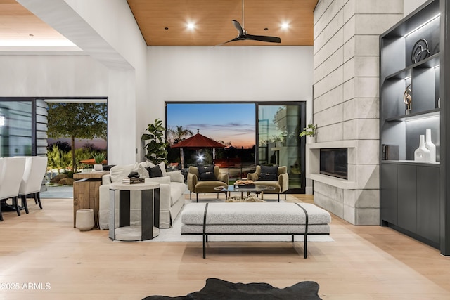 living room featuring wooden ceiling, a tile fireplace, recessed lighting, a high ceiling, and light wood-type flooring