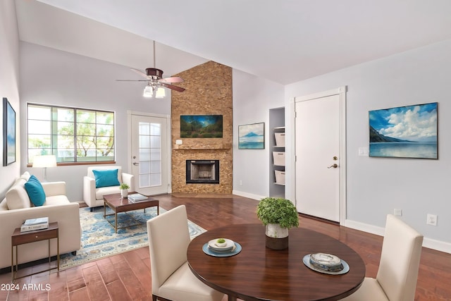 dining space with high vaulted ceiling, ceiling fan, a fireplace, and dark hardwood / wood-style flooring