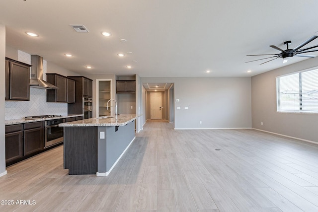 18766 W Montebello Ave, Litchfield Park, AZ 85340 - kitchen with tasteful backsplash, baseboards, visible vents, wall chimney exhaust hood, and ceiling fan