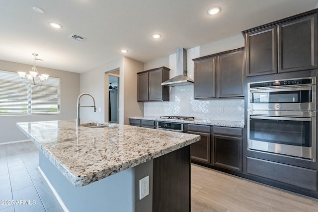 18766 W Montebello Ave, Litchfield Park, AZ 85340 - kitchen with tasteful backsplash, visible vents, wall chimney exhaust hood, stainless steel appliances, and a sink