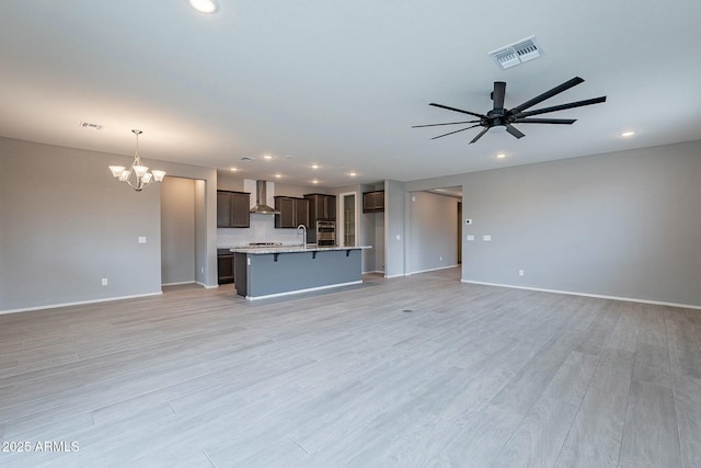 18766 W Montebello Ave, Litchfield Park, AZ 85340 - unfurnished living room featuring ceiling fan with notable chandelier, visible vents, recessed lighting, a sink, and baseboards