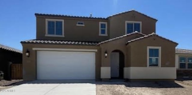 mediterranean / spanish-style home with stucco siding, a tiled roof, an attached garage, and concrete driveway