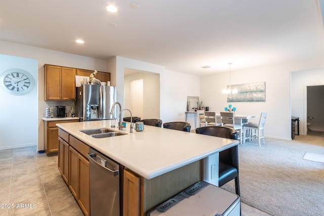 kitchen with appliances with stainless steel finishes, a sink, a chandelier, brown cabinets, and light countertops