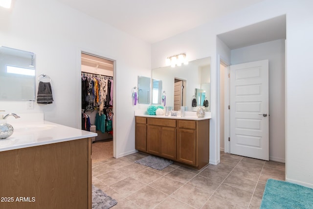 full bath featuring two vanities, a spacious closet, and tile patterned floors