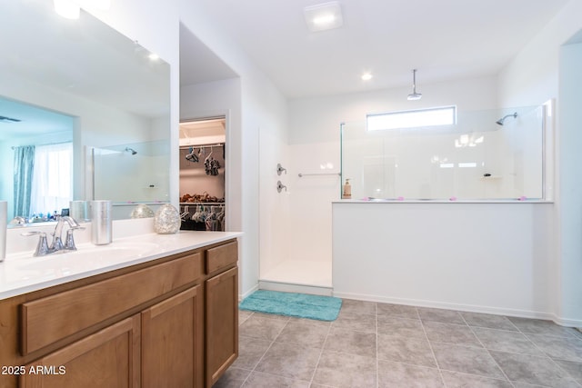 full bathroom with a walk in shower, vanity, a walk in closet, and tile patterned floors