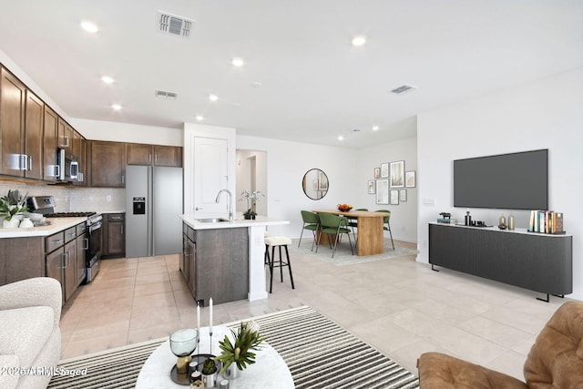 kitchen featuring visible vents, appliances with stainless steel finishes, and an island with sink