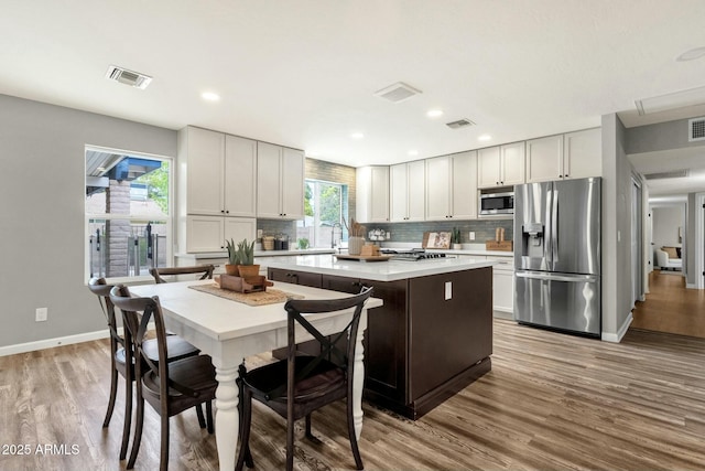 4840 E Sunnyside Dr, Scottsdale, AZ 85254 - kitchen featuring wood finished floors, a kitchen island, backsplash, and appliances with stainless steel finishes