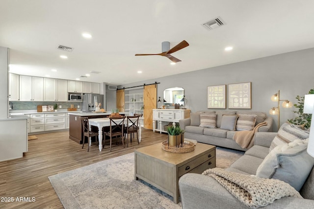 4840 E Sunnyside Dr, Scottsdale, AZ 85254 - living room with a barn door, ceiling fan, visible vents, and light wood-type flooring