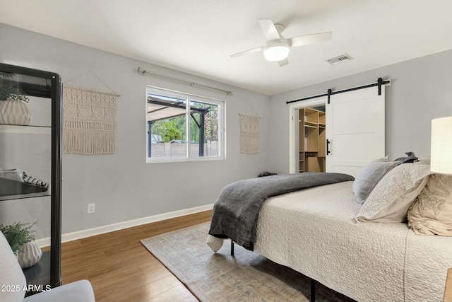 4840 E Sunnyside Dr, Scottsdale, AZ 85254 - bedroom with a barn door, wood finished floors, visible vents, baseboards, and ceiling fan