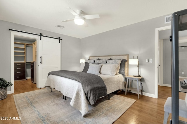 4840 E Sunnyside Dr, Scottsdale, AZ 85254 - bedroom featuring a barn door, wood finished floors, visible vents, and baseboards