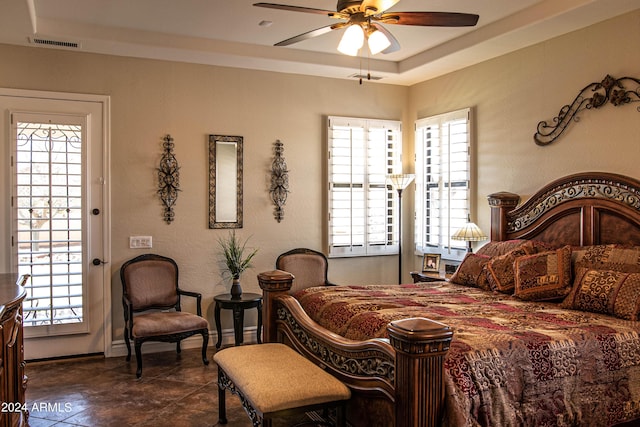 bedroom featuring baseboards, dark tile patterned flooring, a tray ceiling, and visible vents