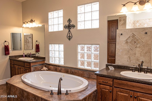 bathroom with plenty of natural light, a whirlpool tub, a sink, and two vanities